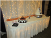 Small lighted cake table with wedding cake and groom cake in the Chisholm Suites
