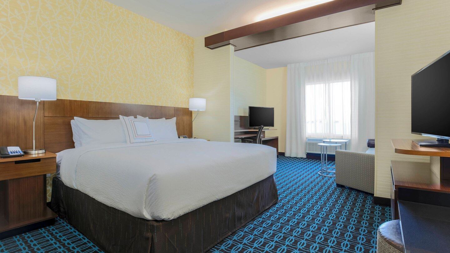 Larger room with one king bed with a sitting area with a desk and lounge chair