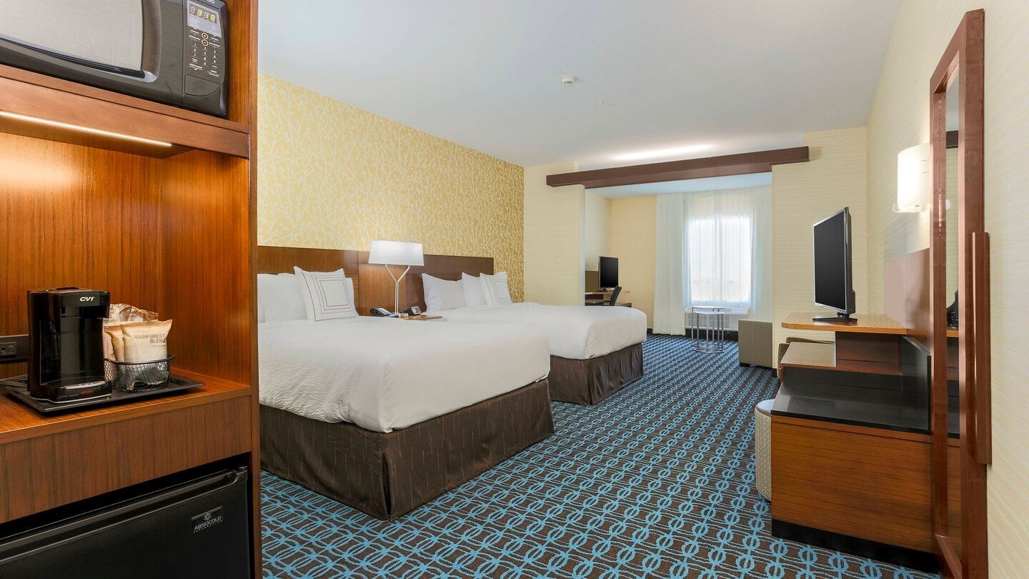 Larger room with two queen beds and a small sitting area with a desk and chair